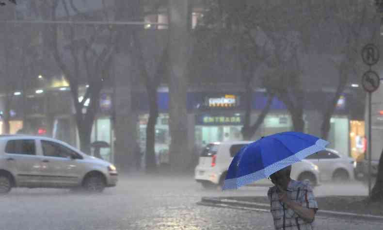 Imagem de uma pessoa andando pela rua com guarda-chuva