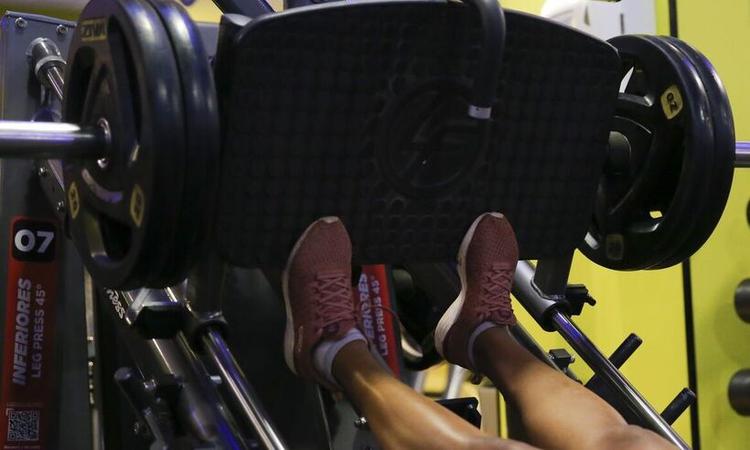 pessoa fazendo exercício em um aparelho de musculação, aparecendo só os pés