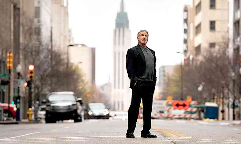 Silvester Stallone est no meio da rua, com prdios ao fundo, em cena da srie Tulsa King