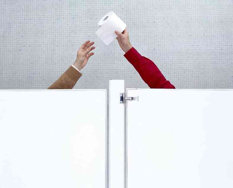 Mos passando papel higinico de uma cabine para outra em banheiro pblico