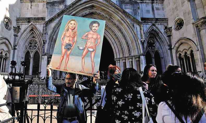 Charge do cartunista Kaya Mar, com Johnny Depp nu, segurando a balança da Justiça, e a atriz Amber Heard, nua, segurando máquina fotográfica, é exibido em frente a Alta Corte de Londres, em julho de 2020