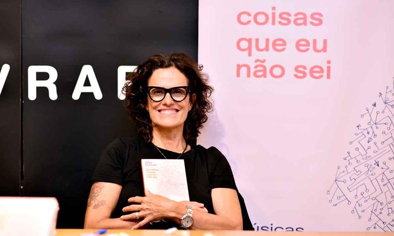 Zlia Duncan olha para a cmera sorri,abraando seu livro Benditas coisas que eu no sei