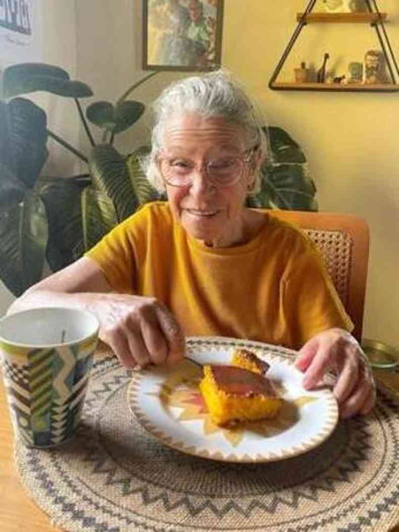 Foto de famlia mostra idosa sorridente e tomando caf com bolo