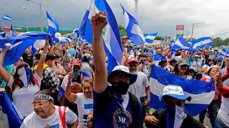 Um protesto na Nicarágua em 2018, com milhares de pessoas vestindo e segurança a bandeira azul e branca do país
