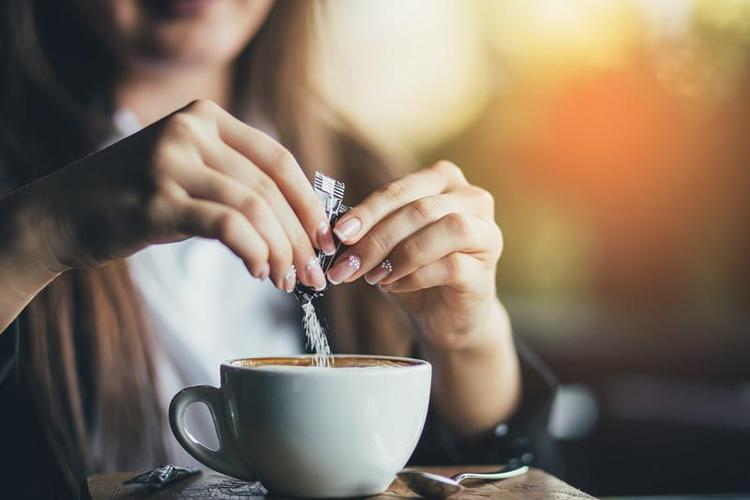 Mulher adoamdo sua bebida com adoante artificial 