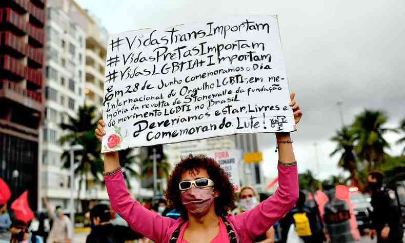 No Rio de Janeiro, manifestante usando mscara ergue cartaz cujos dizeres defendem respeito  vida de negros e da populao LGBT