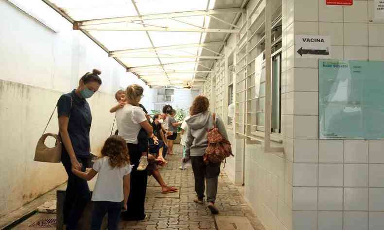 Pais e filhos aguardam na fila de posto de saúde, em BH, para tomar a vacina pediátrica contra a COVID