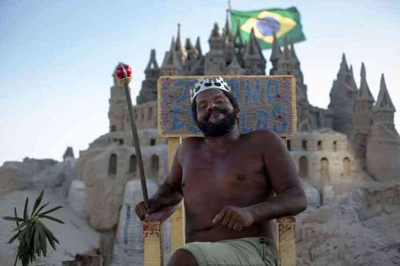 Marcio assume a majestade para atrair curiosos e posa com boa vontade para fotos com cetro em punho no trono que instalou em frente ao seu castelo praiano(foto: Mauro Pimentel/AFP)