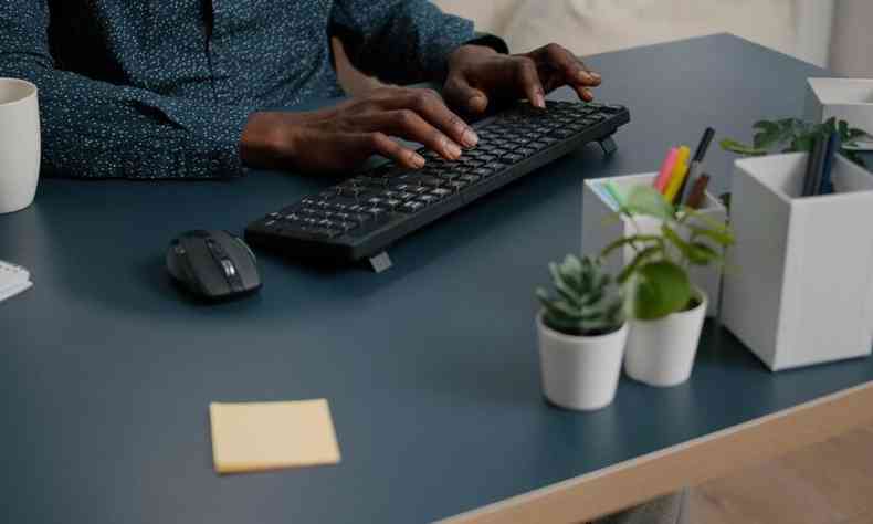 Vista superior das mos de uma pessoa negra digitando em um teclado