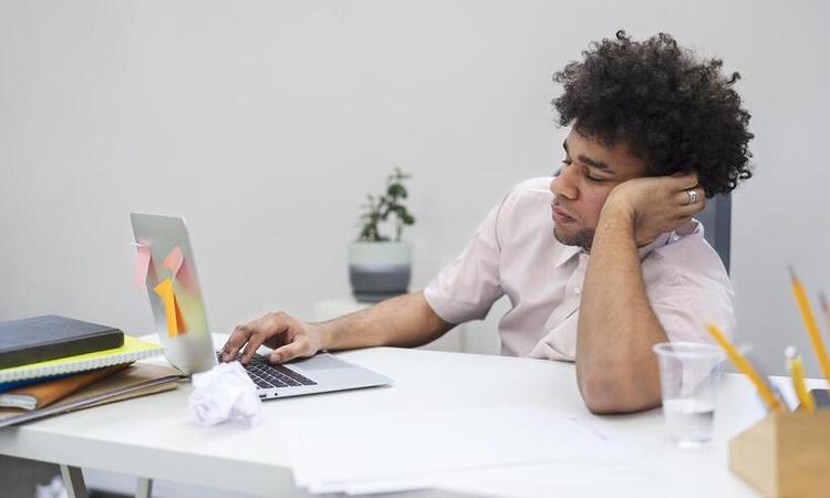 Homem entediado com laptop no trabalho