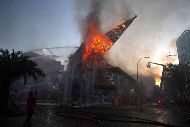 Homens encapuzados atearam fogo a igrejas em Santiago e %u201Ccelebraram%u201D queda da torre de uma delas (foto: Claudio Reyes/AFP)