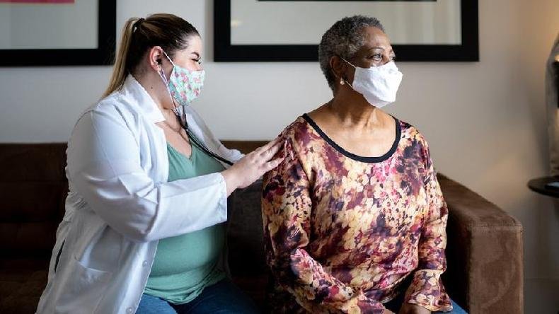 Profissional de sa�de analisa a respira��o de uma mulher idosa