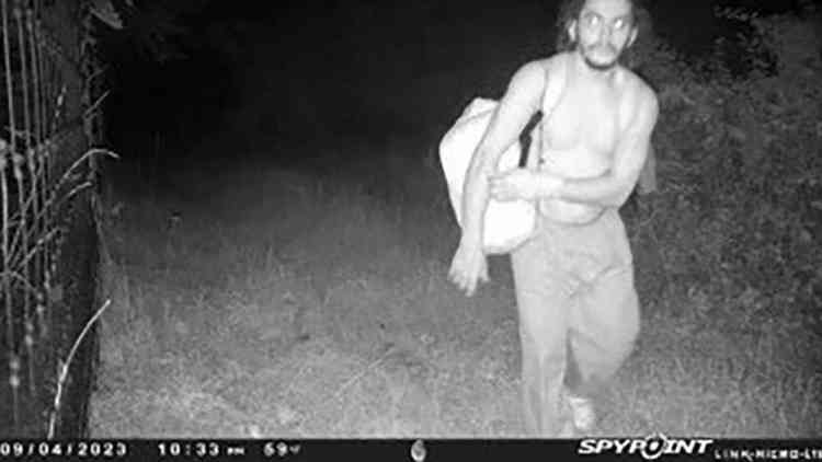 Foto em preto e branco mostra homeme sem camisa no mato à noite