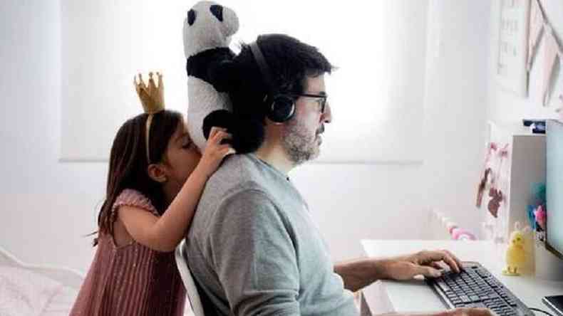 Garota brinca enquanto o pai trabalha em frente ao computador
