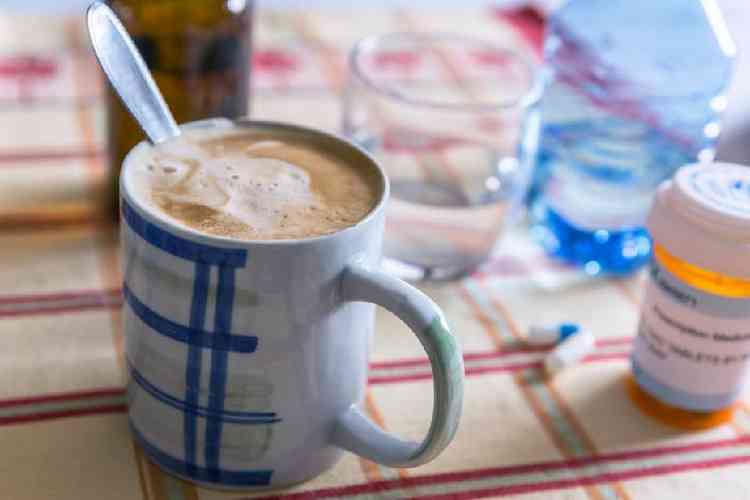 Xcara de caf com leite ao lado de um comprimido sobre uma mesa