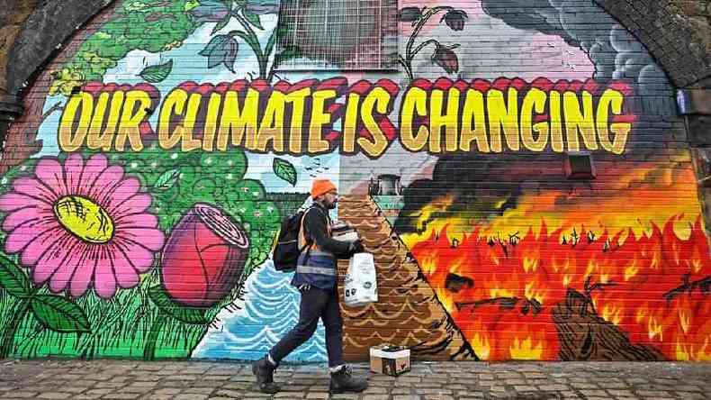 Homem passa na frente de mural na cidade de Glasgow, onde ocorre a COP26