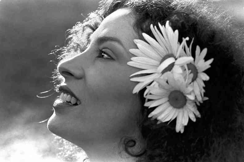 foto p&b com o rosto de perfil de Clara Nunes, com flores no cabelo 