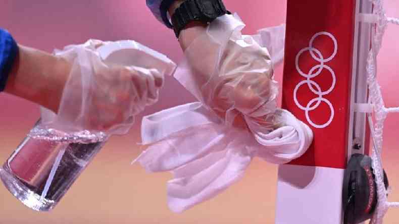 Um voluntrio desinfeta o mastro de uma baliza de handebol durante uma partida nas Olimpadas(foto: Getty Images)
