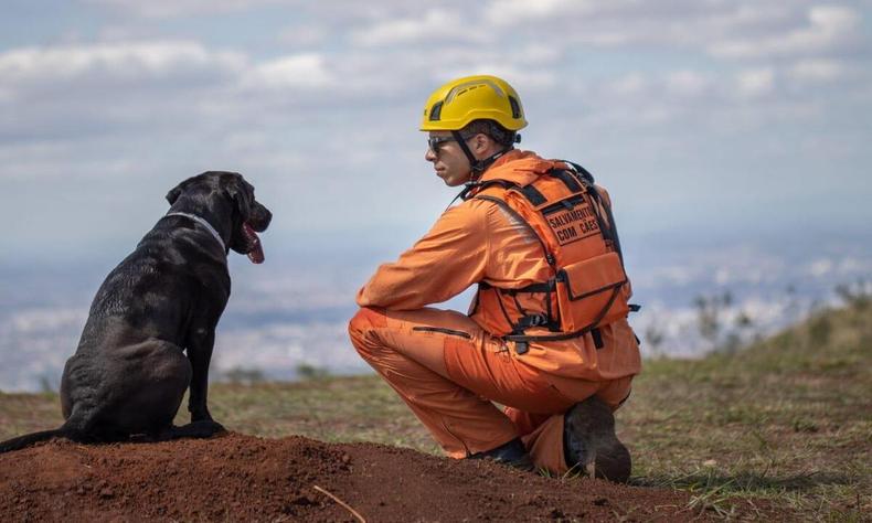 Agente do Corpo de Bombeiros Militar de Minas Gerais ao lado de um cachorro