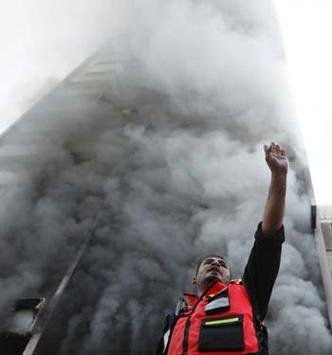 Ap�s ataque israelense que atingiu pr�dio que re�ne escrit�rios de imprensa, bombeiro palestino sinaliza para colegas em Gaza(foto: REUTERS/Suhaib Salem)