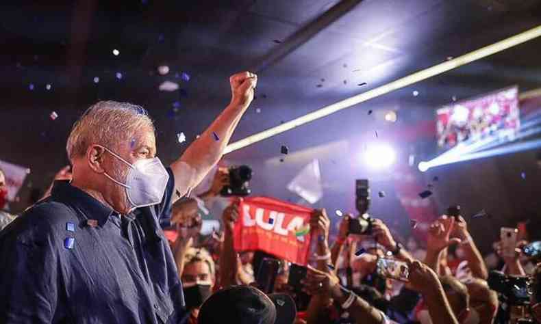 Lula de mscara e brao levantado diante de apoiadores 