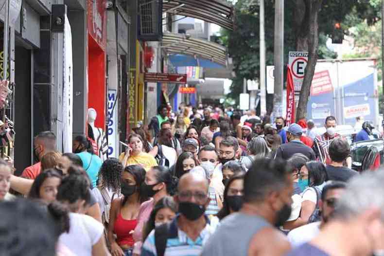Multidão de consumidores transitando com sacolas e máscaras pela Rua dos Carijós para compras natalinas