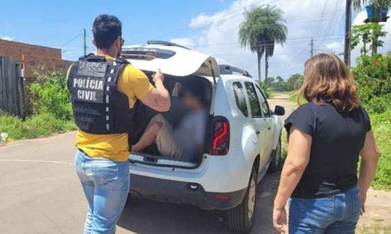 Homem sendo colocado no porta malas de uma viatura da Polcia Civil