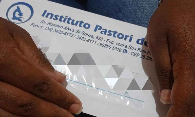 Mãe da vítima segura envelope com resultado de exame de sangue feito em sua filha, de 4 anos (foto: Samir Alouan/Rádio 97FM) Imagem de envelope de exame nas mãos da mãe da criança