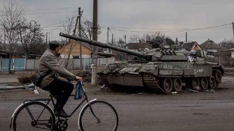 Um homem passa de bicicleta por um tanque russo destrudo em 30 de maro de 2022 em Trostyanets, Ucrnia