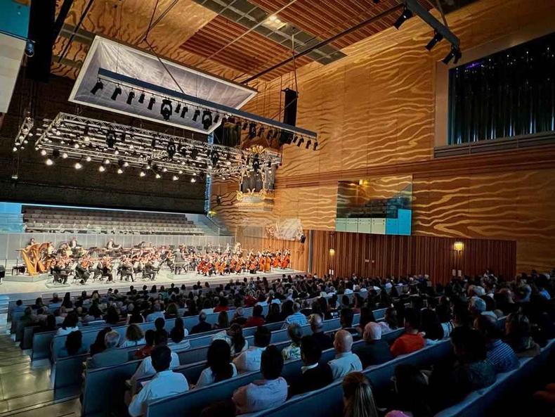 Grupo de pessoas assiste a apresentao de orquestra