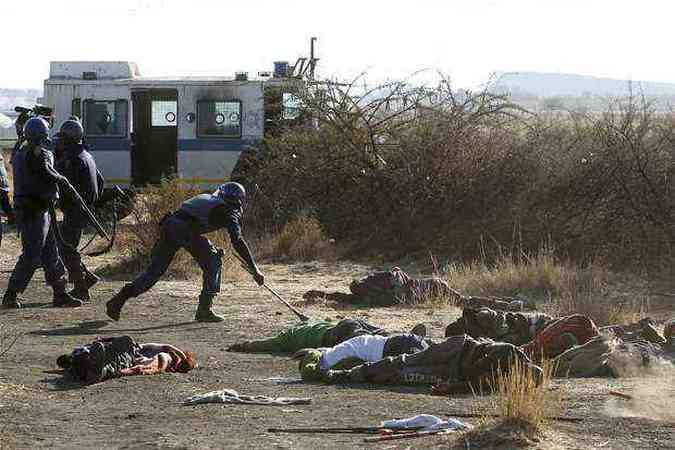 Policiais andam entre os corpos dos mineiros mortos para recolher o material usado pelos trabalhadores no confronto(foto: REUTERS/Siphiwe Sibeko)