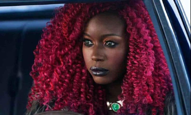 Anna Diop, mulher negra retinta com cabelos cacheados vermelhos 