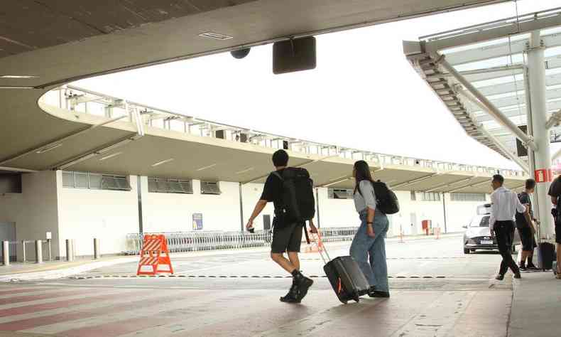 Imagem de pessoas com malas de viagem na entrada de um aeroporto