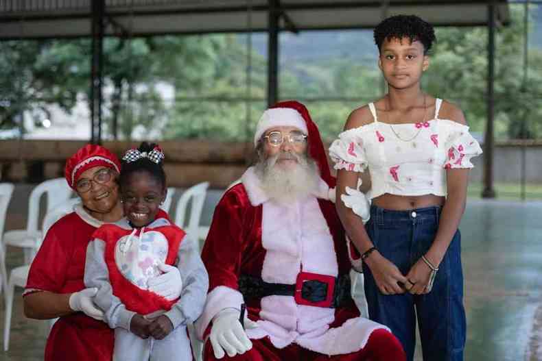 Foto mostra a Mame Noel negra com o Papai Noel e duas meninas negras 