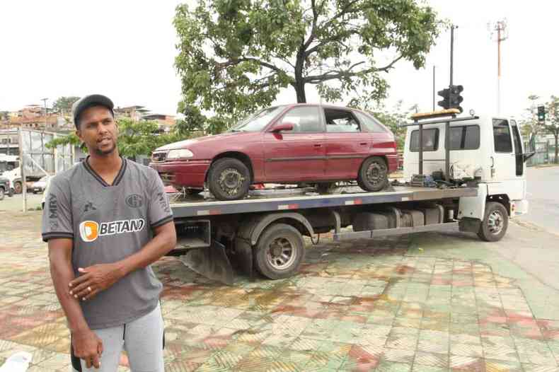 Homem diante do carro sobre um caminho reboque