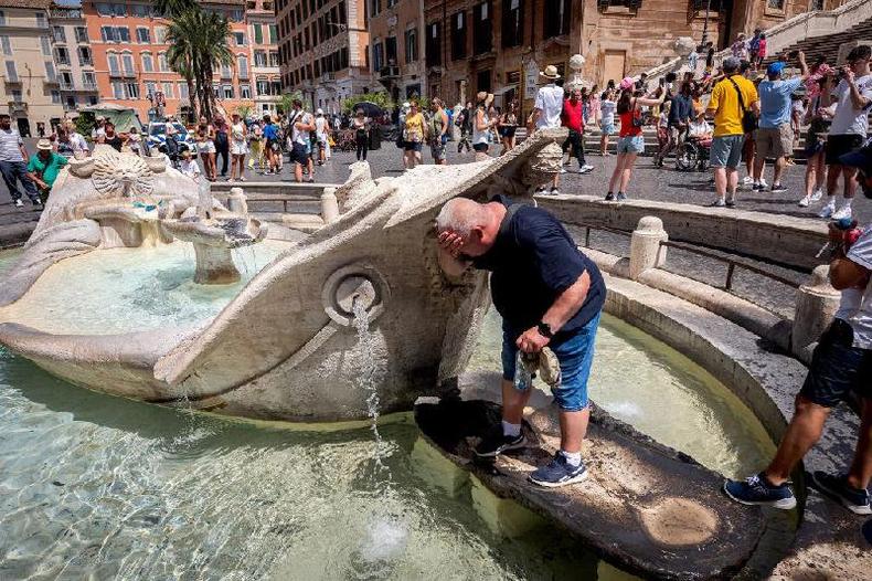 Um homem se refresca em uma fonte de gua para escapar do calor