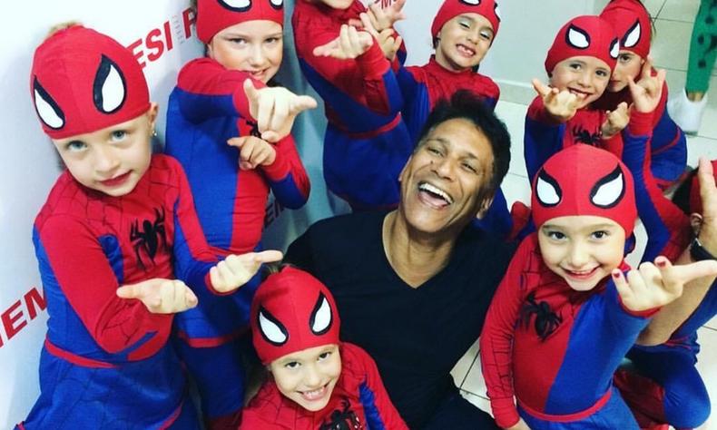 O bailarino Eurico Justino cercado de pequenas alunas(foto: Eurico Justino/Instagram/reprodução) Bailarino Eurico Justino sorri no meio de crianças fantasiadas de Homem Aranha