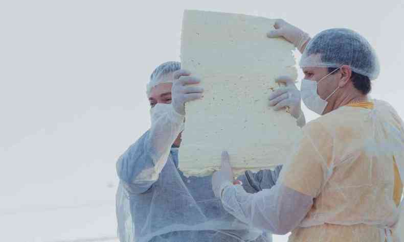 Pessoas exibindo um pedao do maior queijo minas padro do mundo