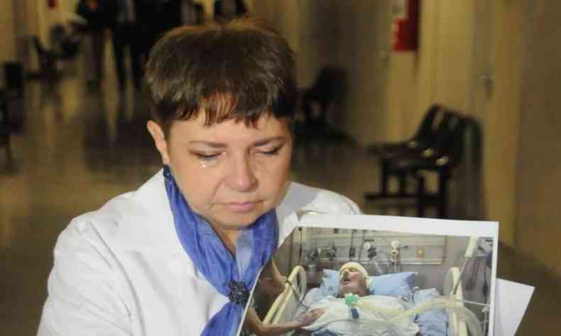 Imagem da viúva mostrando uma foto do marido no hospital