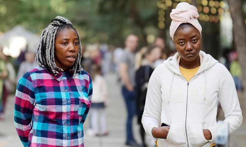 Duas jovens em p, paradas, em um espao ao ar livre