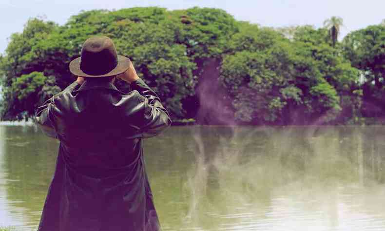 Homem usa binculos para ver ilha no filme A ilha da ponta da lagoa