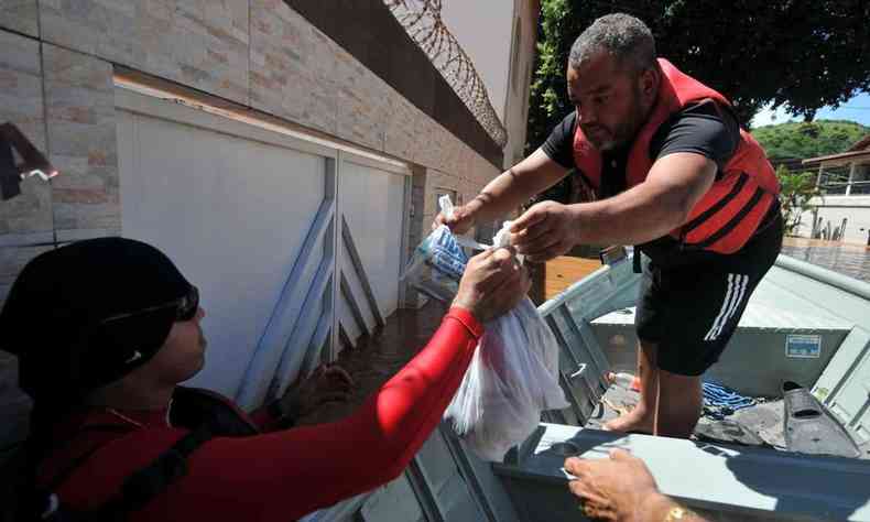 Voluntrio e Militar do Corpo de Bombeiros levando remdios para uma famlia ilhada