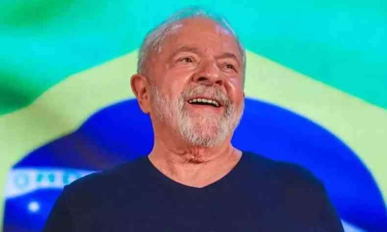 Lula, de camisa preta, com a bandeira do Brasil ao fundo