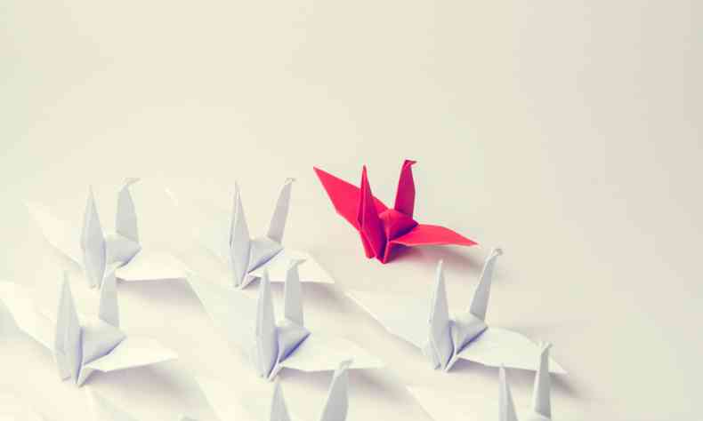 Foto de alguns origamis no formato de passarinho. Apenas o que est  frente na cor vermelha e os demais na cor branca.