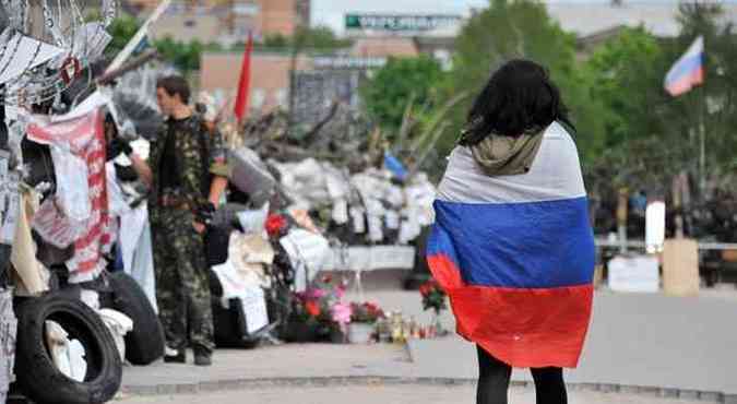 Mulher com bandeira russa anda em frente  sede do governo de Donetsk, que est invadida por separatistas pr-Rssia(foto: GENYA SAVILOV/AFP)