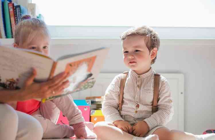 Crianas sentadas olhando livro