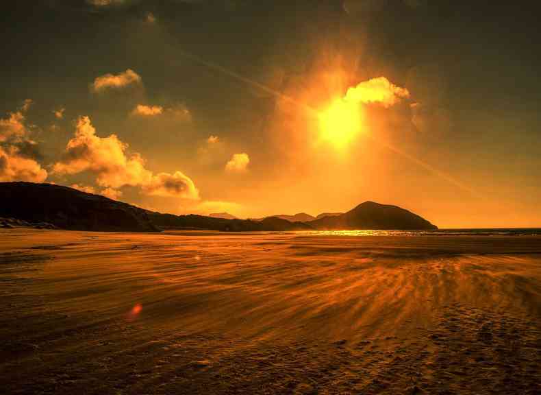 Imagem meramente ilustrativa de praia com sol