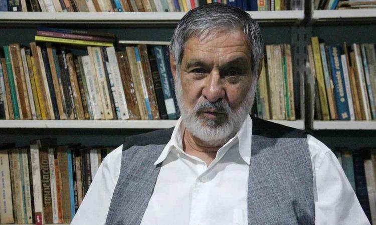 Braz Chediak olha para a cmera, tendo ao fundo livros de uma estante
