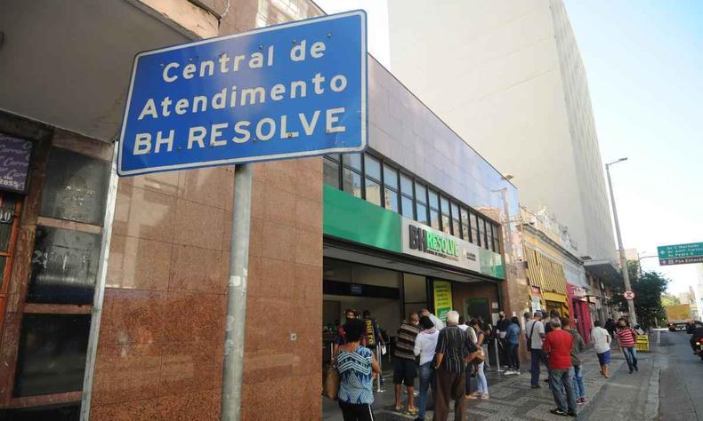 Fachada do BH resolve, na frente uma placa escrito 'central de atendimento bh resolve', em azul. Atrs pessoas na porta da unidade.