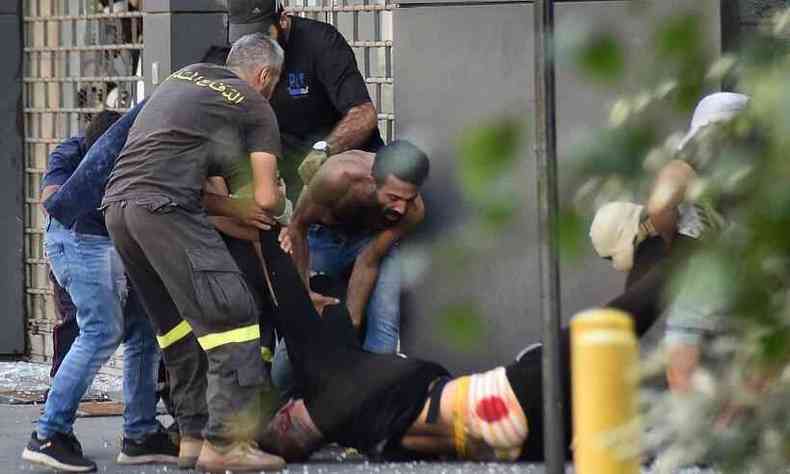 Homem ferido  carregado por companheiros durante tiroteio nas ruas de Beirute